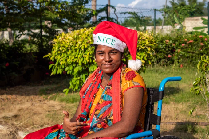 teen girl in wheelchair with thumbs up wearing a santa hat
