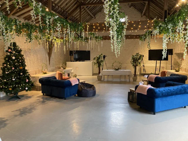 blue sofas arranged around an AV set up. Interior of barn.