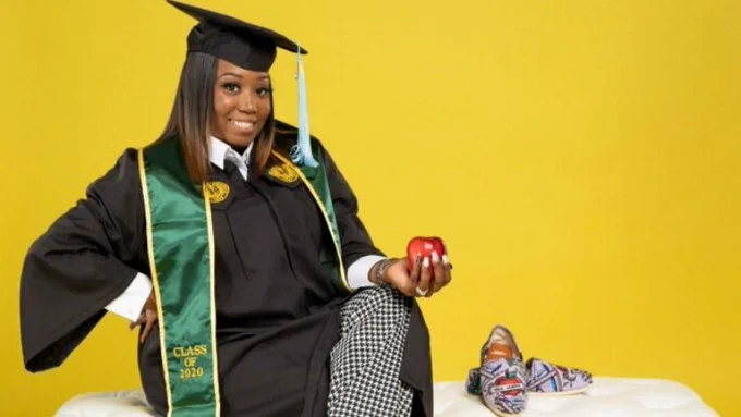 Woman wearing graduation gown and holding an apple 