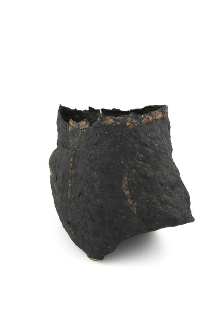 A roughly textured stoneware vessel with dark brown black surface and streaks of orange 
