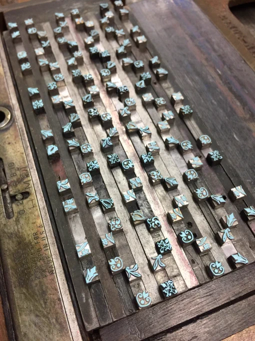 the letterpress printing form for the blue part of the pattern, which is a repeating grid of small, floral, handset lead ornaments.