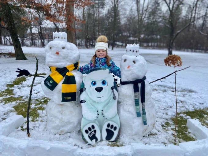 Little girl standing behind a snowman wearing a Wayne State University scarf