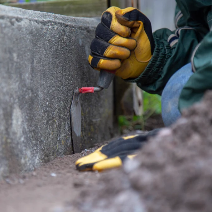 Close up on the hands of a volunteer from Rebuilding Together Dutchess County using a spade to shore up the steps of a home rebuild in Poughkeepsie.