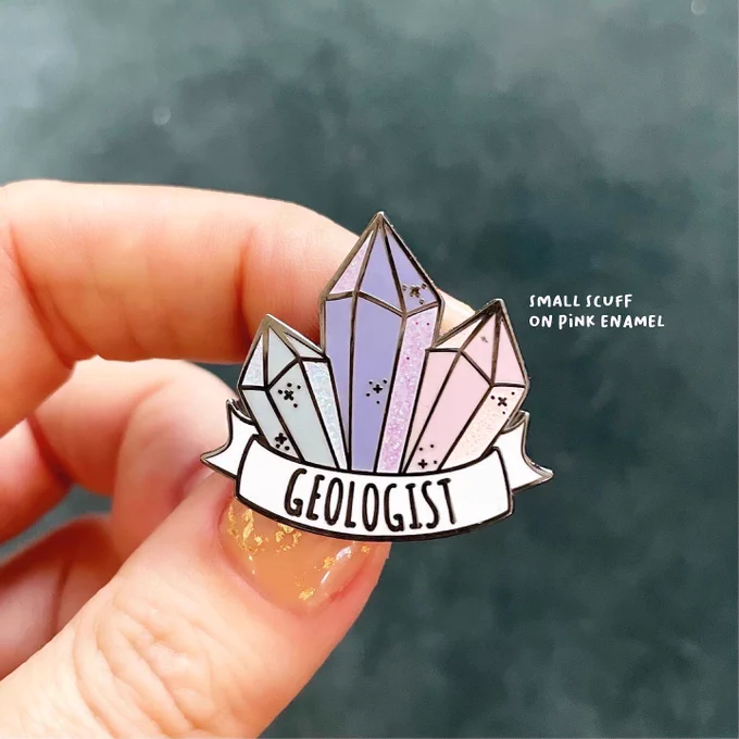 Photo of an enamel pin with a label describing a small imperfection.