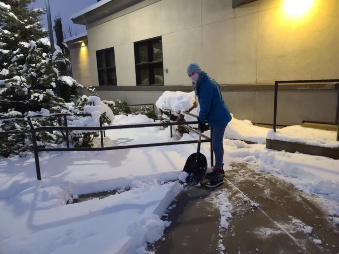 Stephanie Edmonds, Assistant Director, Custodial and Support Services shoveling a walkway on campus.