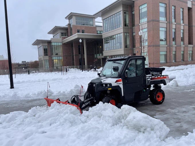 A snow CAT clearing snow in front of the Pennington Student Achievement Center