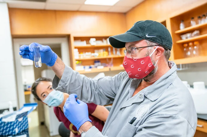 Geoff Holm, Associate Professor of Biology, along with Michelle Landstrom, Surveillance and Monitoring Technician, prepare waste water samples that were collected with a GLS Sampler to be analyzed for the presence of COVID-19 around the Colgate University campus.
