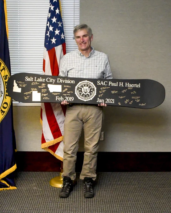Special Agent in Charge Paul Haertel holding a Salt Lake City FBI-personalized snowboard.
