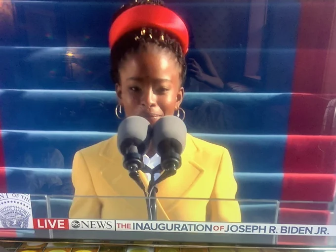 Photo of Amanda Gorman in a yellow coat speaking at the inauguration.