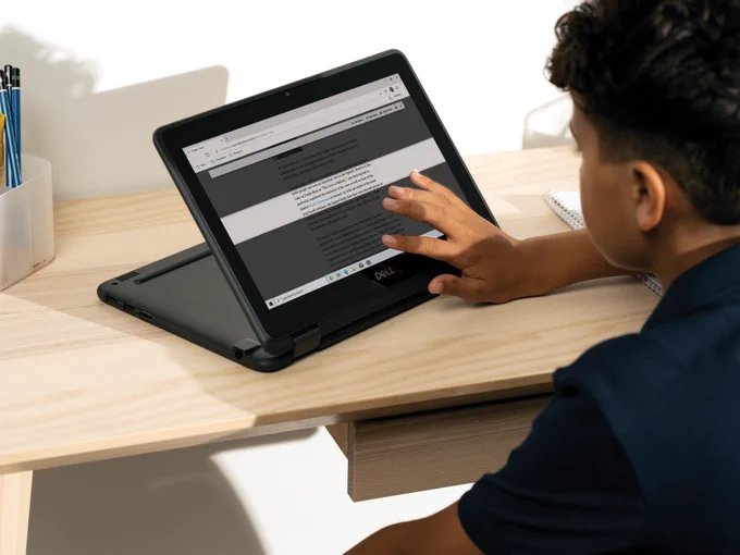 Elementary school age child at a desk with Immersive Reader on the screen. 