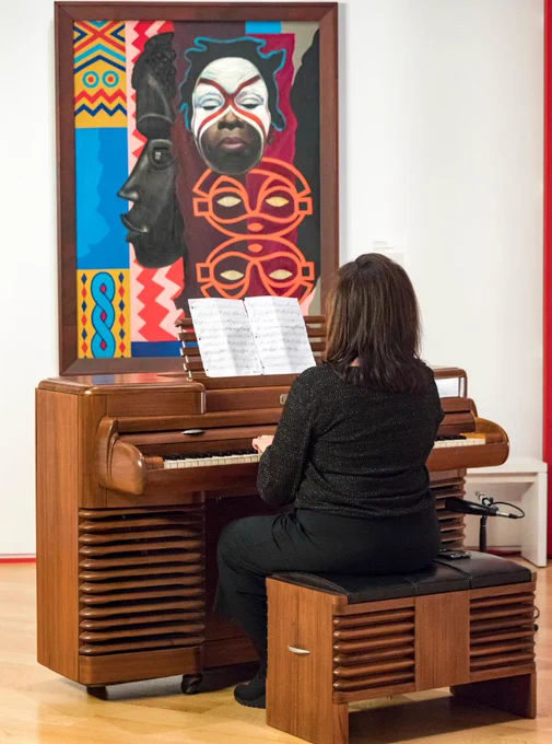 Woman plays piano in front of a painting
