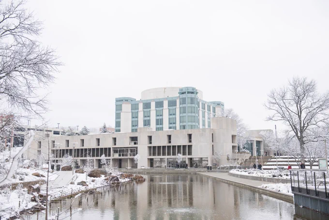 Exterior view of campus library and pond with snow on the ground
