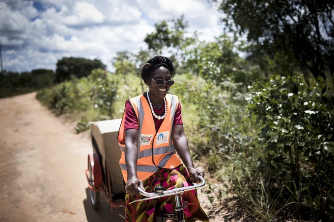 Woman on bicycle in Zambia delivering medicine