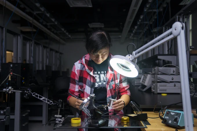 a female engineering student looks at items under a ring light. 