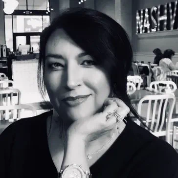 A gorgeous woman sitting in a cafe with her chin on her hand. Photo in black and white.