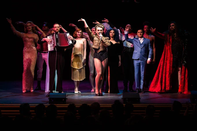 Cast of Queer Lates x Queerhistory on stage, waving at the audience. 