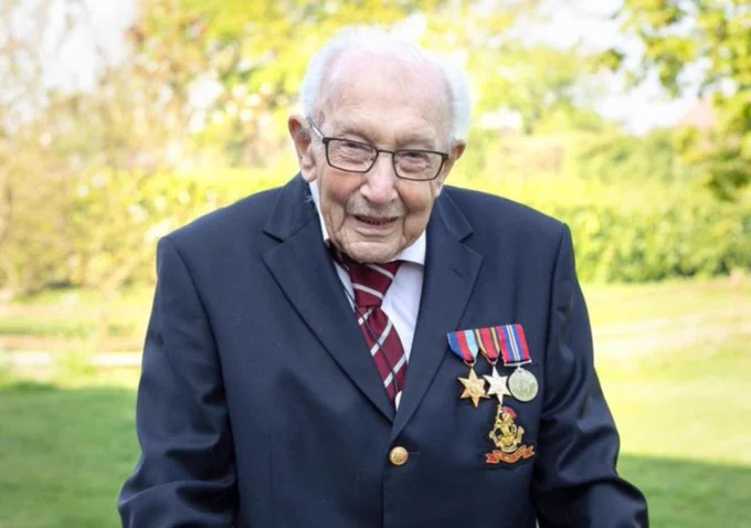 Captain Sir Tom outside in the sun, wearing his medals and smiling into the camera.