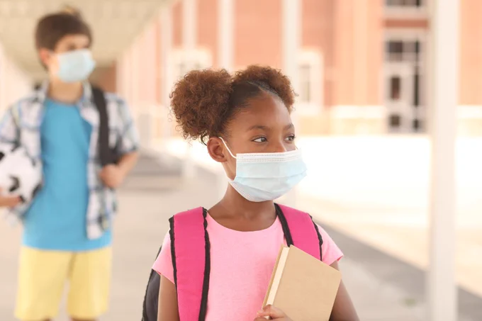 Schoolchildren with masks and carrying books. Social distanced.