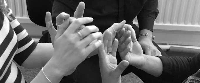 image focuses on the hands of three people in conversation using using tactile sign
