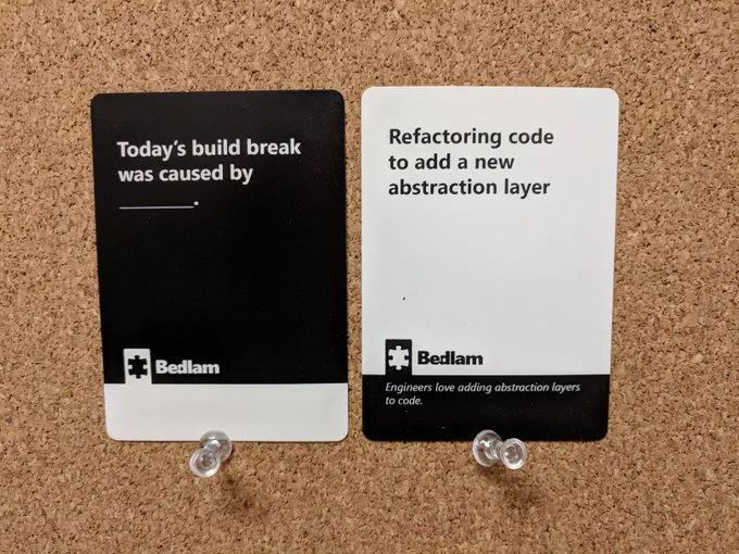 Two cards from the game Bedlam. One says "Today's build break was caused by" with a fill in the blank. The other says "Refactoring code to add a new abstraction layer"