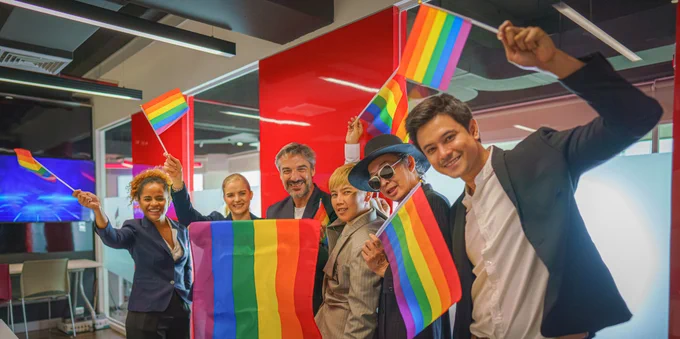 Group of people at work waving the rainbow flag