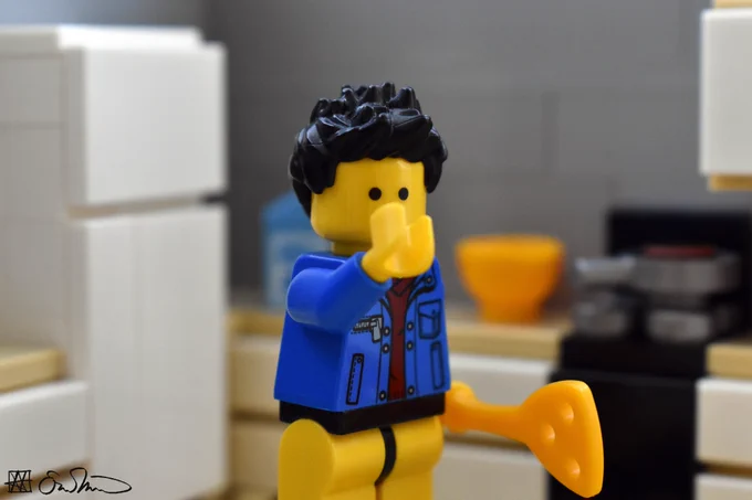 LGS covers his mouth with his hand. He stands in his kitchen and is holding a spatula. He is not wearing pants.