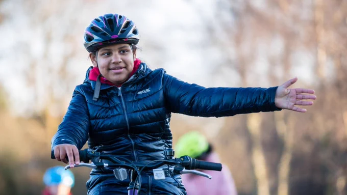 Child cycling and indicating with hand