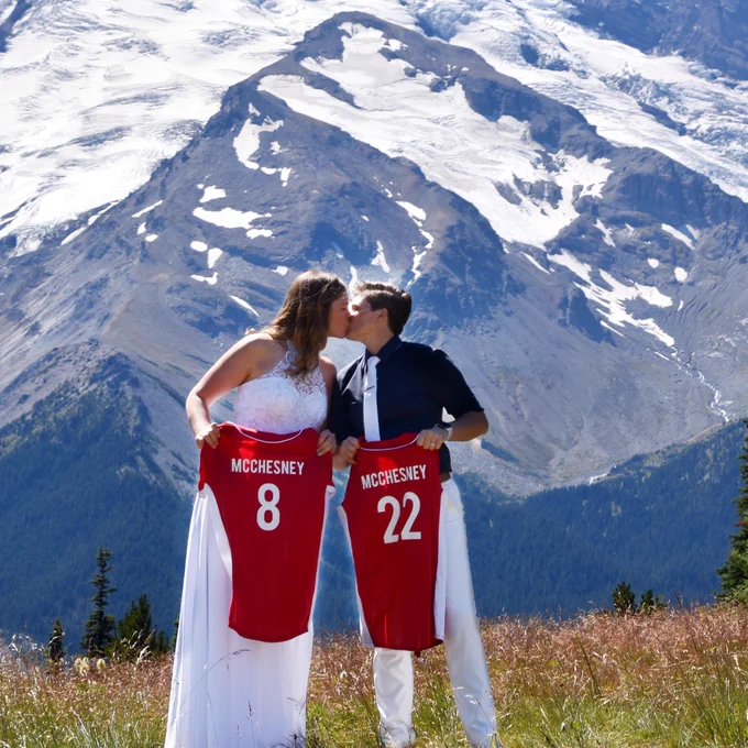 Miami Mergers Kylie McChesney ’15 and Amber Logemann ’16 celebrating their love with mountains in the background and their softball jerseys in hand. 