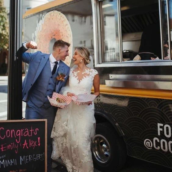 Miami Mergers Emily and Alex in their wedding attire enjoying a Crunch n Munch Bagel at Miami alum run Cocky's Bagels in the Cleveland. 