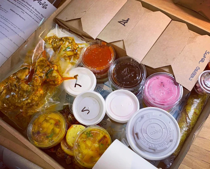 Card box box filled with more cardboard boxes and recyclable plastic pots of Indian food and dips.