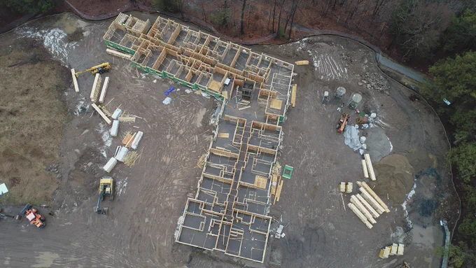 Overhead drone shot of L-shaped building framed out in construction