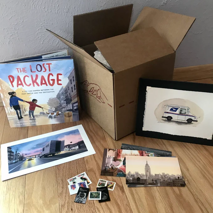 Photo of cardboard box sitting on the floor surrounded by a picture book titled The Lost Package, a print of a truck and car driving on city street at dawn, a small painting of a USPS mail truck, and assorted postcards and stamps.