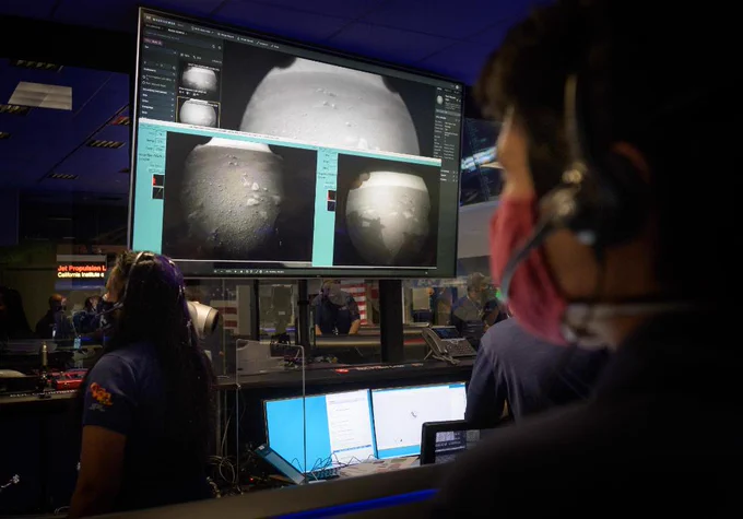 Members of NASA’s Perseverance Mars rover team watch in mission control as the first images arrive moments after the spacecraft successfully touched down on Mars, Thursday, Feb. 18, 2021, at NASA's Jet Propulsion Laboratory in Pasadena, California. A key objective for Perseverance’s mission on Mars is astrobiology, including the search for signs of ancient microbial life. The rover will characterize the planet’s geology and past climate, pave the way for human exploration of the Red Planet, and be the first mission to collect and cache Martian rock and regolith. Photo Credit: (NASA/Bill Ingalls)