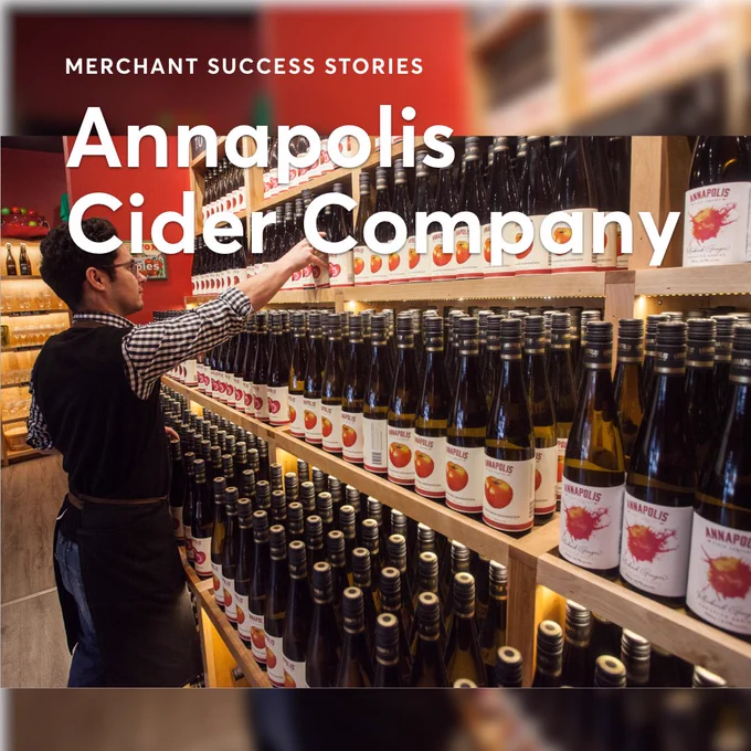 A man in a vest stocks a shelf with bottles on it. Text shown: Merchant Success Stories: Annapolis Cider Company
