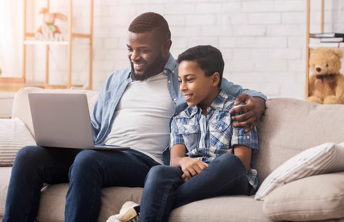 Father with son on laptop attending virtual psychotherapy appointment.