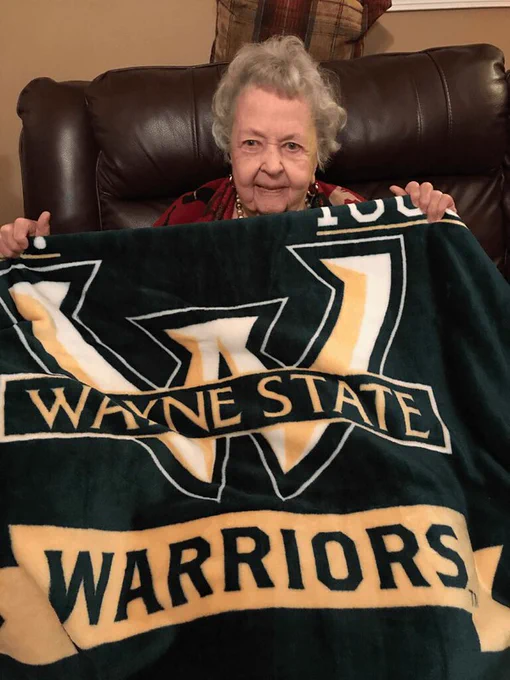 Woman holding a blanket with Wayne State Warriors on it