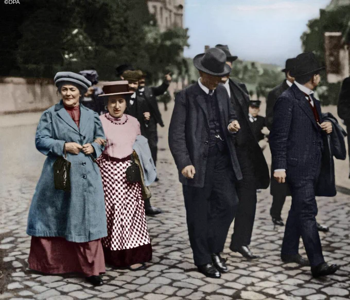 Clara and Rosa alongside a group of men in suits, colorized
