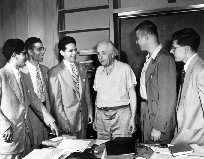 an older Einstein with students in suits.
