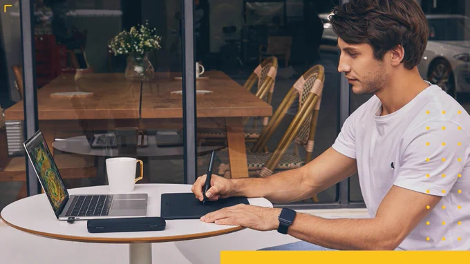 Person drawing on the Xencelabs Pen Tablet from a cafe patio.