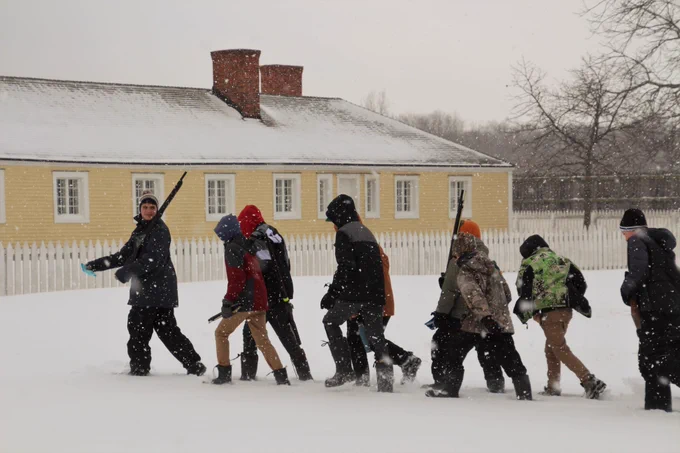 Scouts marching in single file through snow flurry.