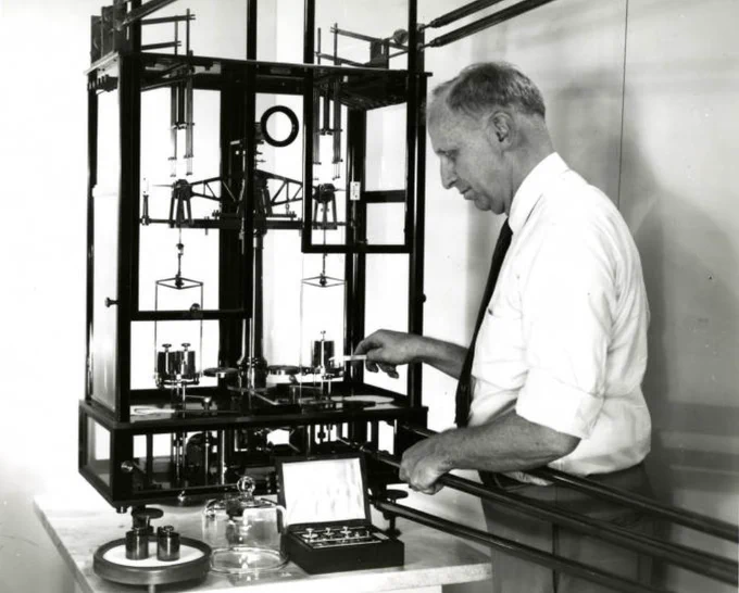 Researcher loading weights onto a balance scale.