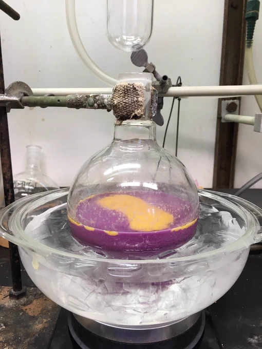 the same 1000 mL round bottom, now with patches of orange floating on top of the bright purple solution