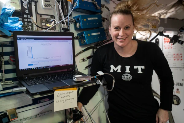 Astronaut Kate Rubins wears an M.I.T. sweater and smiles as she works aboard the Space Station.