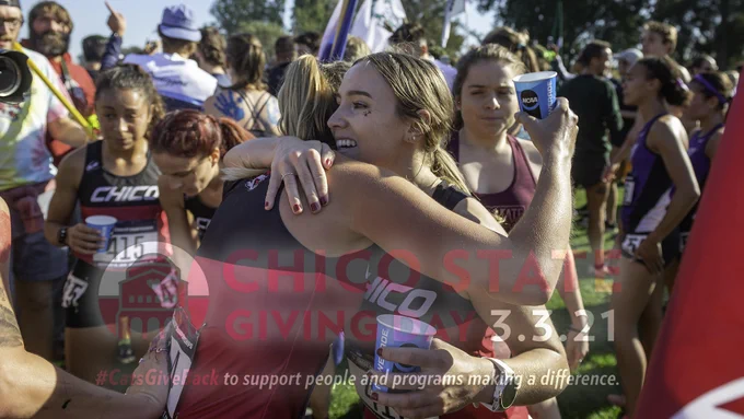 Members of the Chico State women's cross country embrace and catch their breath following their run at the 2019 NCAA Championships at Haggin Oaks Golf Course in Sacramento on Saturday, November 23, 2019. The photo, taken by University Photographer Jason Halley, is overlaid with a cardinal, gray and white logo that includes an artistic rendering of Kendall hall and the words: Chico State Giving Day 3.3.21 #CatsGive Back to support people and programs making a difference.