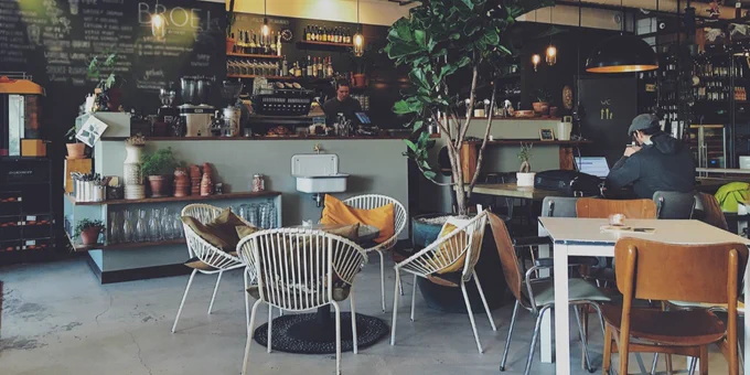 hotel lobby with a cafe featuring plants and a sitting area of white chairs