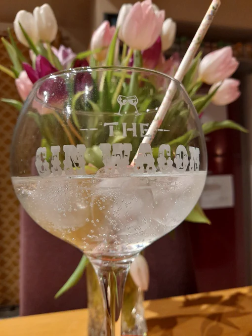 Glass of gin in front of flowers