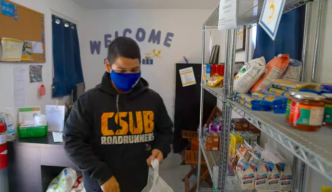 CSUB student walking through food pantry wearing a csub sweater and face mask. 
