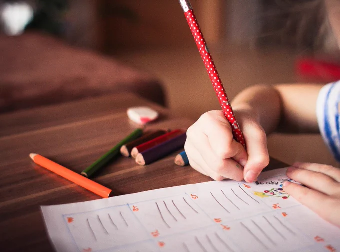 Child writing and drawing on a notepad that they've ruled into four lines.