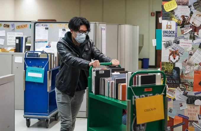 A student worker pushes a book truck.
