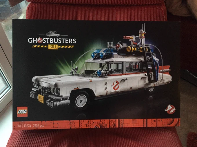 Box of the LEGO Ecto 1 (2020 version) sat on a red chair